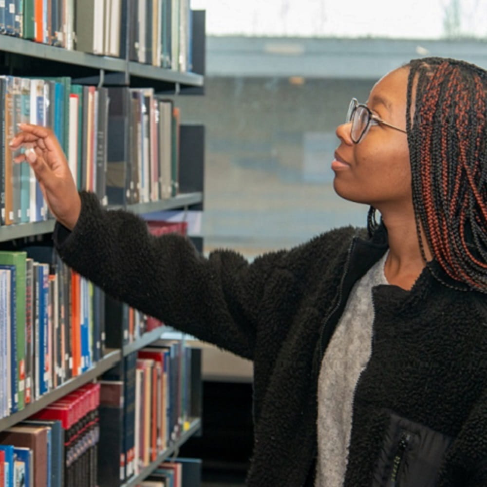 Student selecting a book from a shelf in the library