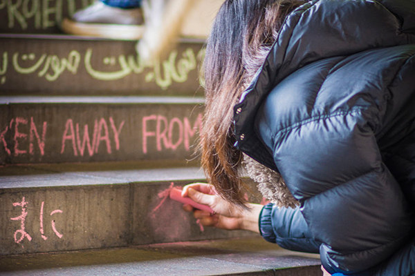 Student chalking the Colchester Campus steps for Human Rights Week