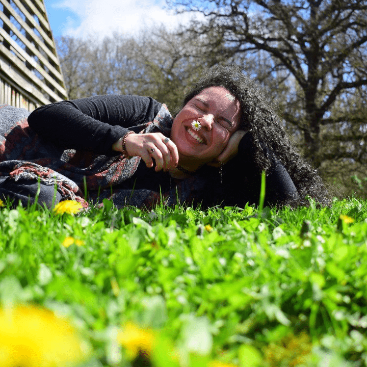 A student laying on the grass and smiling.