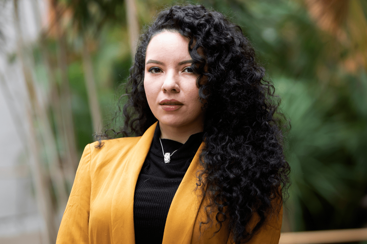 Headshot of MBA student Luisa. She is wearing a yellow blazer and has curly hair.