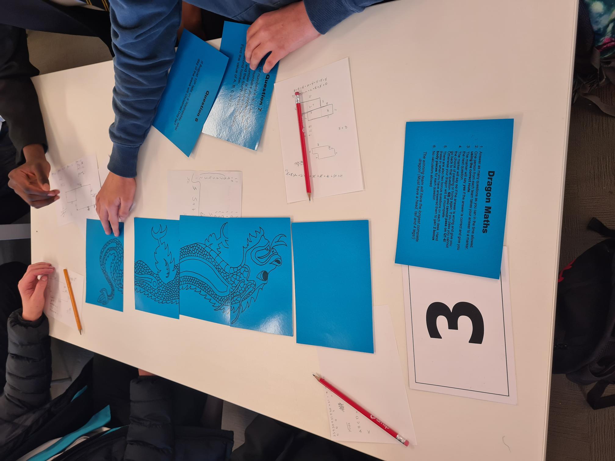 Children drawing dragon on a table on blue paper