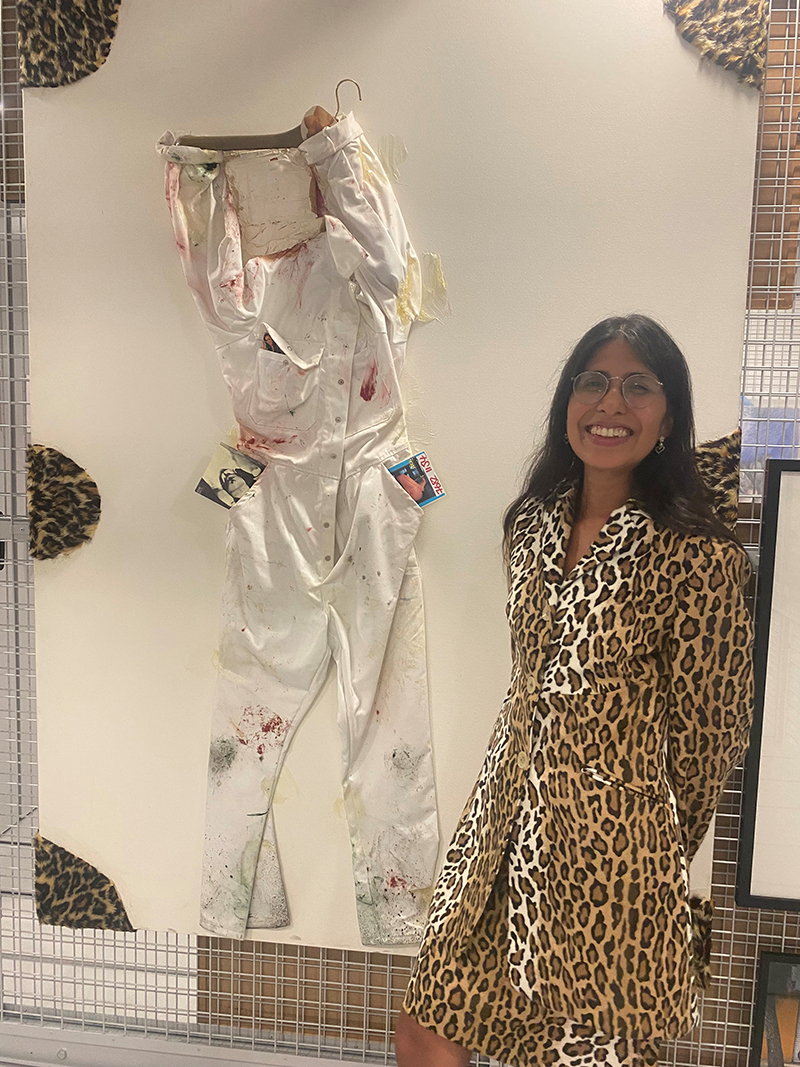 Assistant Curator of ESCALA and the University Art Collection, Gisselle Giron wears 1990s matching faux fur Leopard skirt suit by the diffusion line of Franco Moschino, Cheap and Chic and stands next to Siron Franco’s “Self-Portrait” (2001) in the ESCALA Teaching and Research Space.