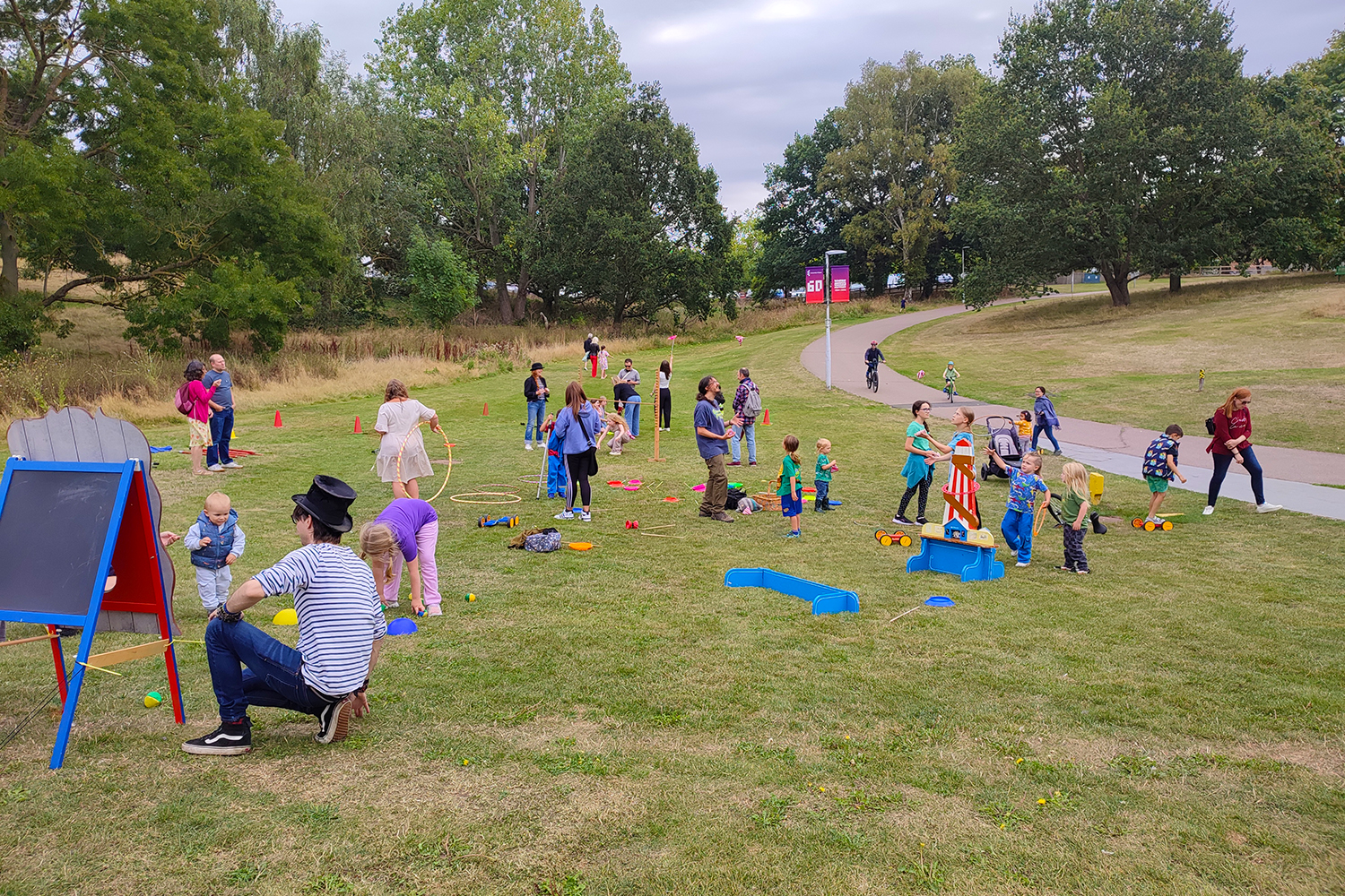 a large group of families with young children practice circus skills on the grounds of the university of essex