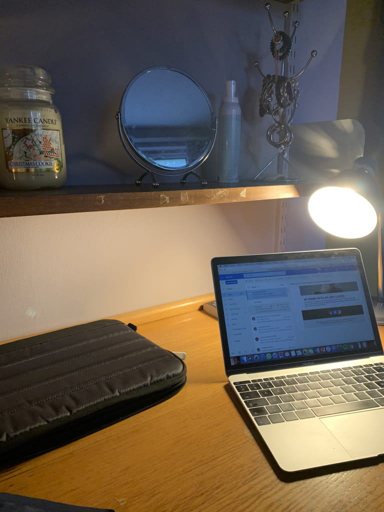 Laptop on a desk with a desk lamp on