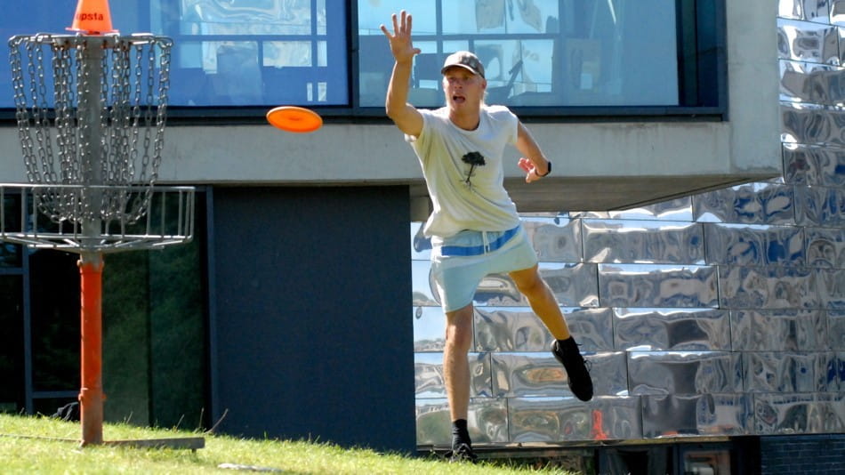 student playing throwing frisbee in game of disc golf