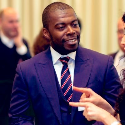 Andrew in a blue suit and tie, people in the background