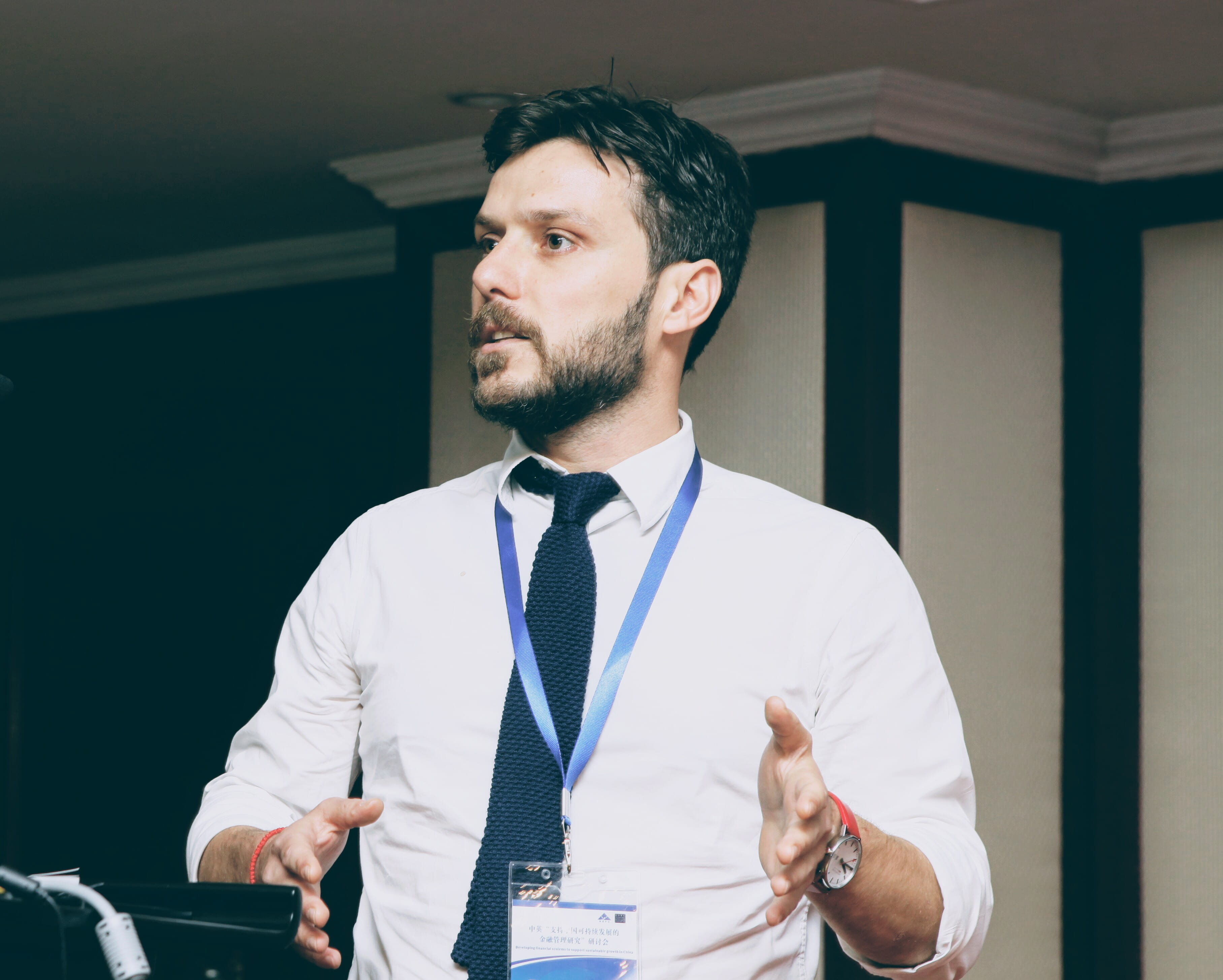 Dr Thanos Verousis, Reader in Finance, stands at a lectern as he teaches postgraduate Finance students