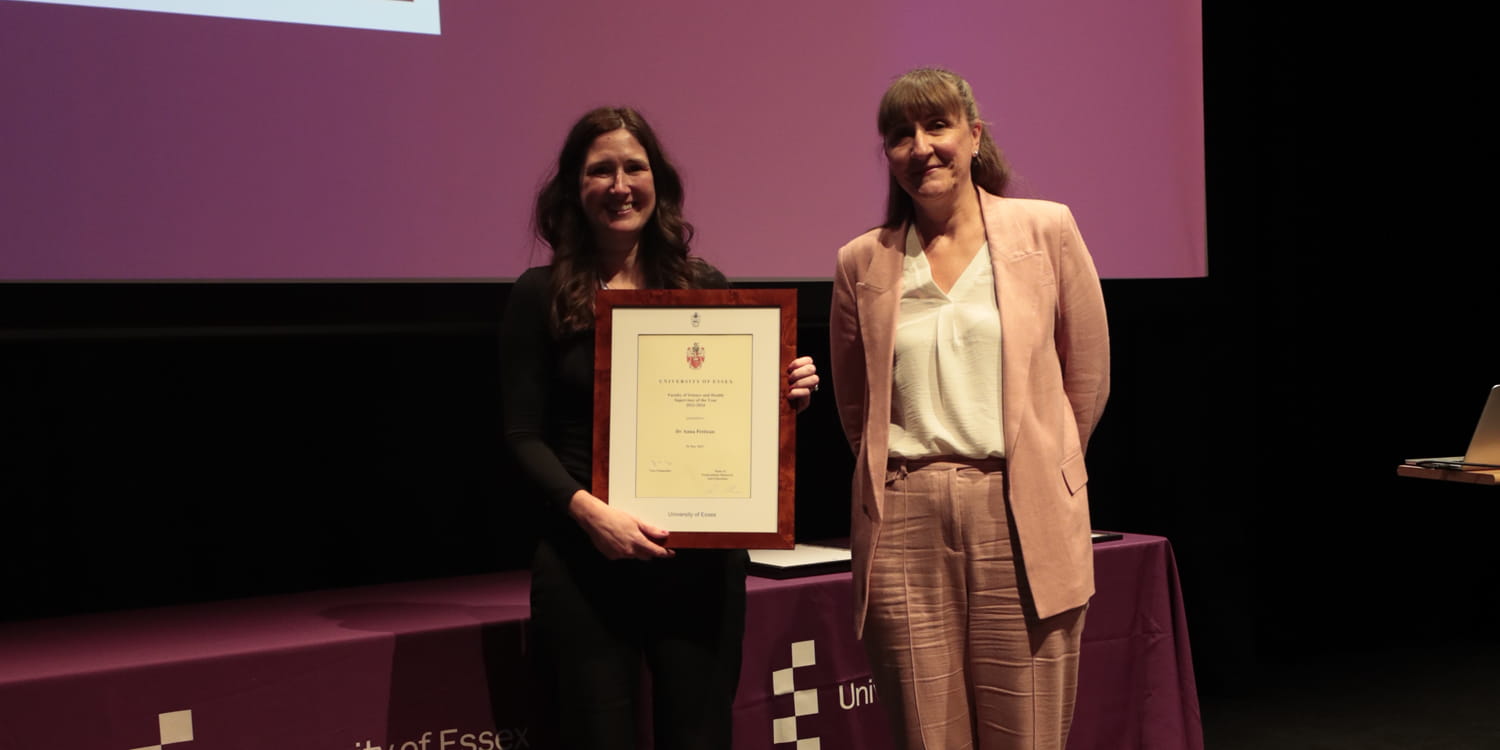 Dr Anna PETTICAN receives a framed certificate on stage.