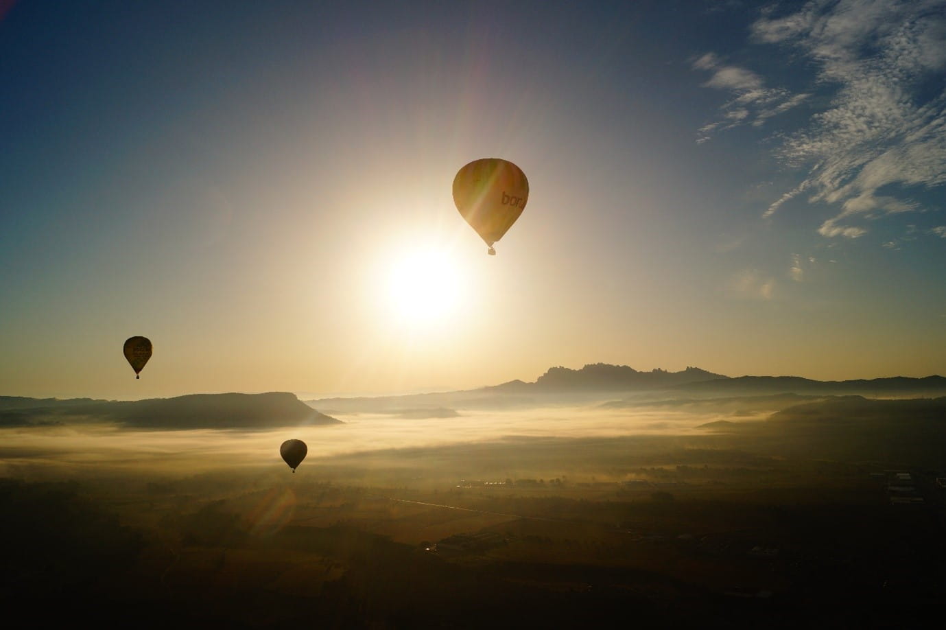 3 hot air balloons over a sunset sky in barcelona