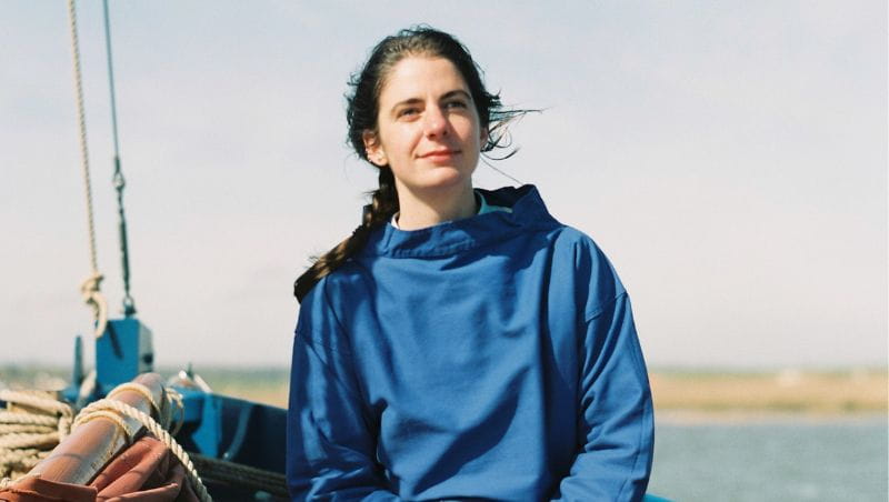 Rose Ravetz, sitting on a boat with the wind in her hair, looking off into the middle distance