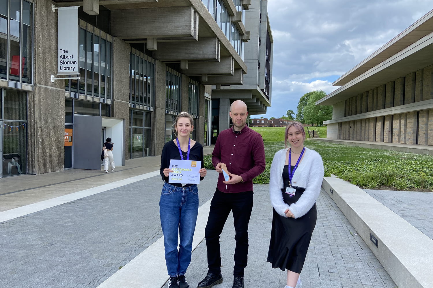 Library and Cultural Services Sustainability Team members Krysta Lynch, Marcus Goulding and Beth Burnett hold their Sustainable Essex Gold Award in front of the Albert Sloman Library