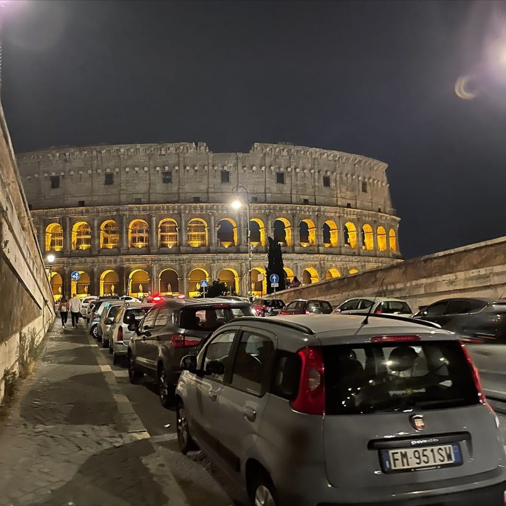 A night time view of the Colosseum in Rome with a Fiat in the foreground 