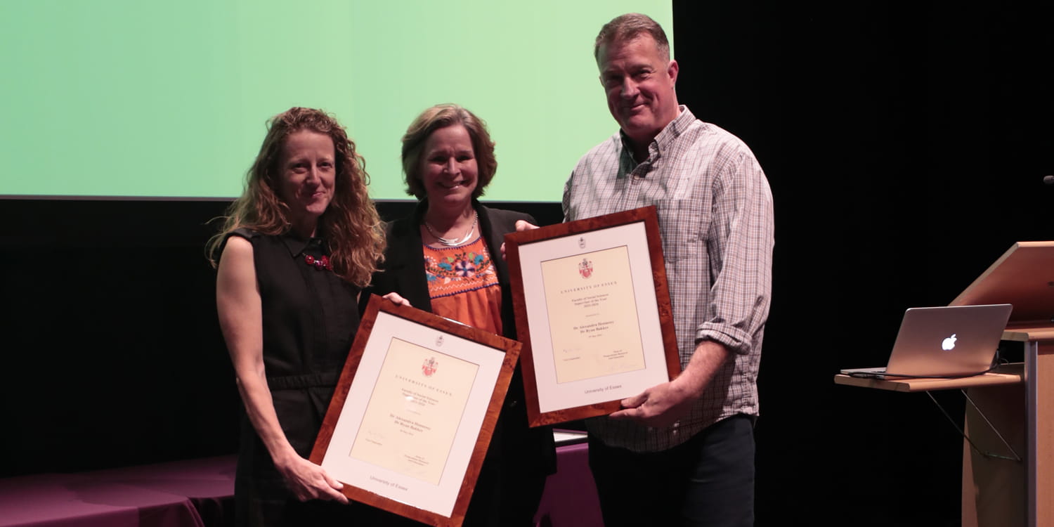 Dr Alexandra HENNESSY and Dr Ryan BAKKER receive framed certificates on stage.