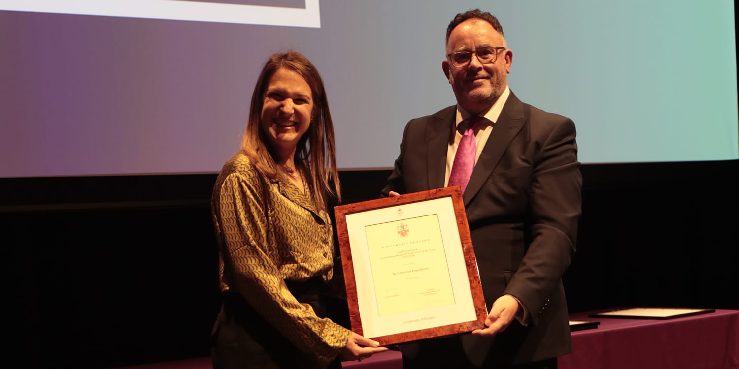 Dr Christina KAPADOCHA receives a framed certificate on stage.