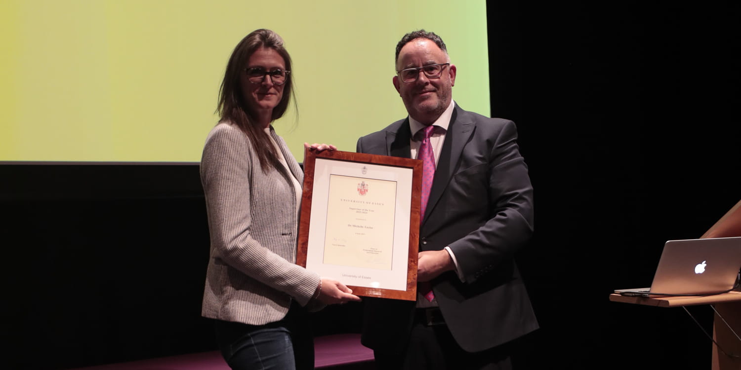 Dr Michelle TAYLOR receives a framed certificate on stage.