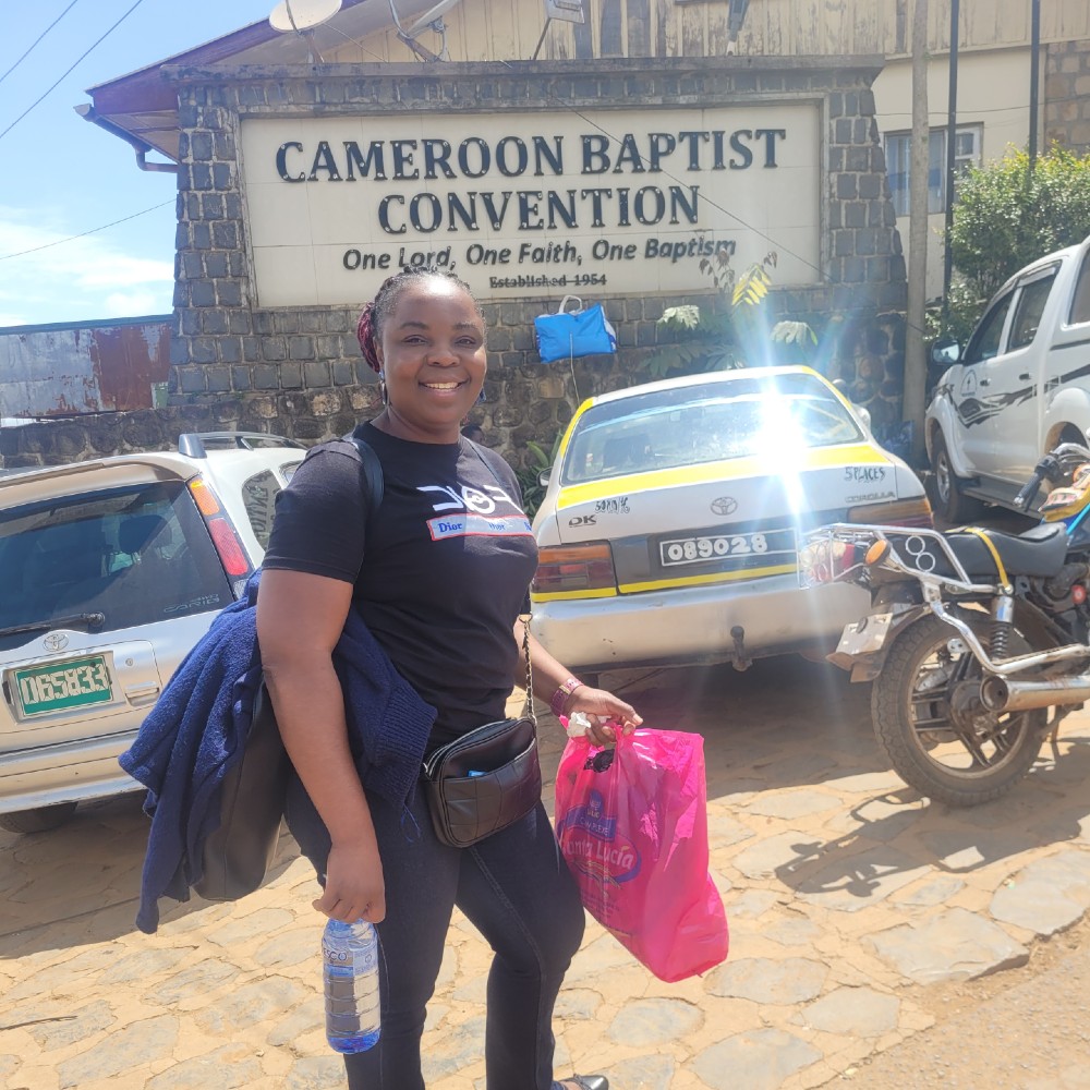 A student stands smiling outside the Cameroon Baptist Convention