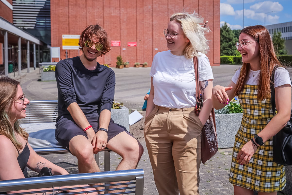 Four students chatting outside in the sunshine