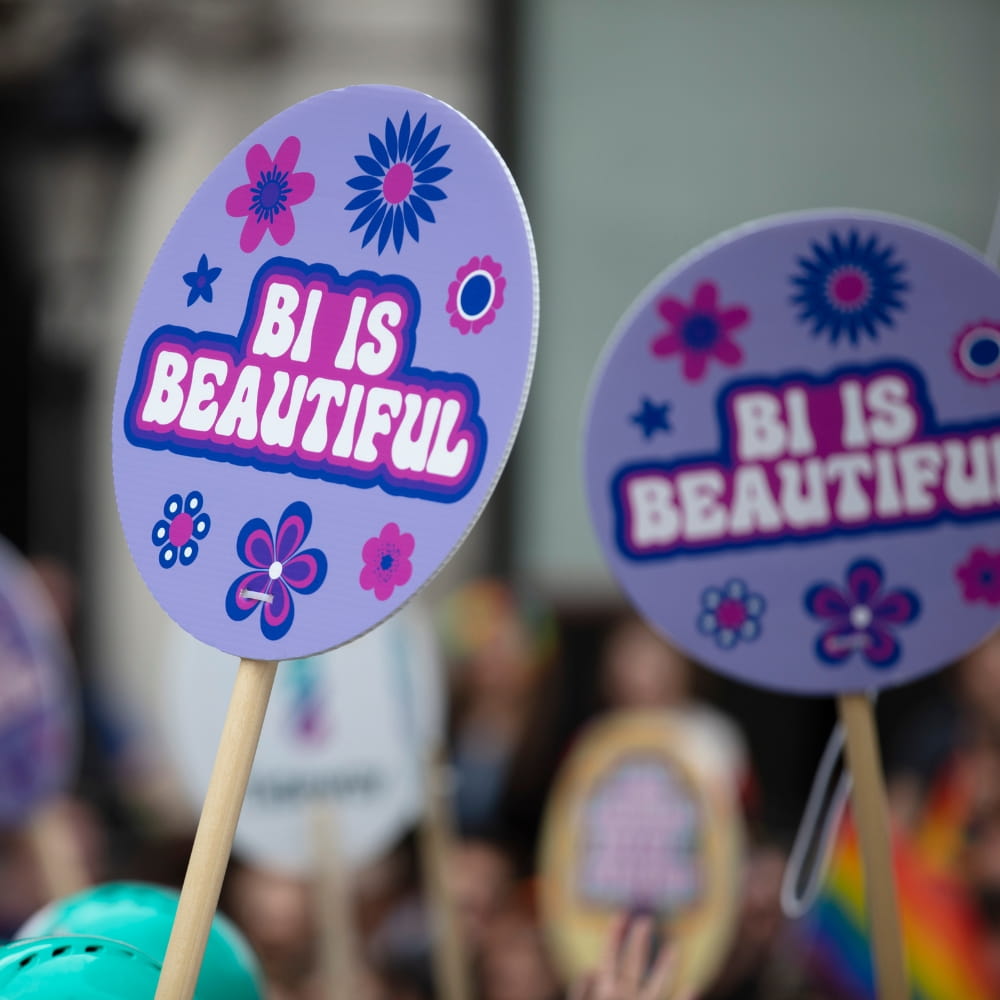 Two placards held aloft. The words 'BI IS BEAUTIFUL' is emblazoned upon them.