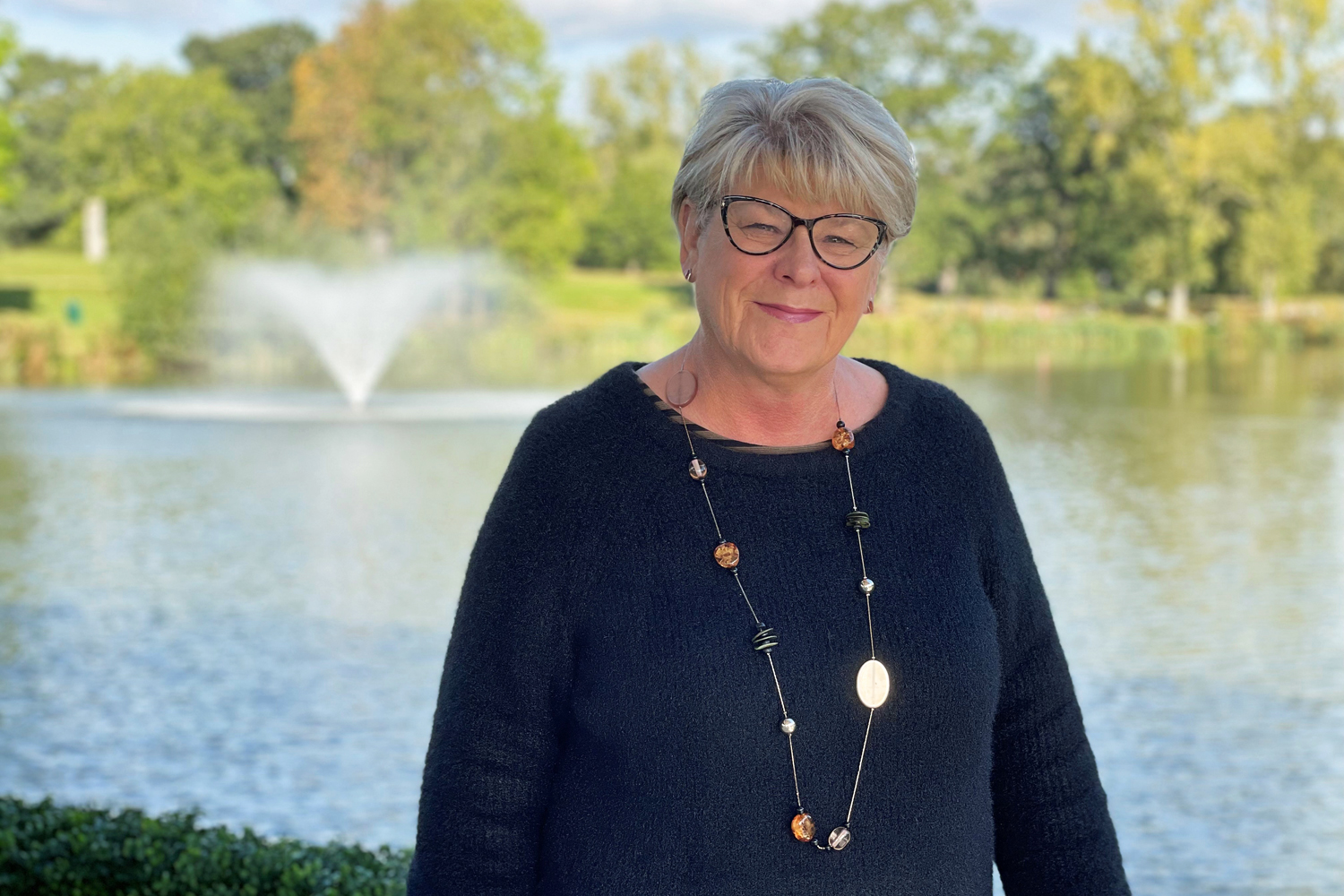 Julie Procter stood by the lake at our Colchester Campus.