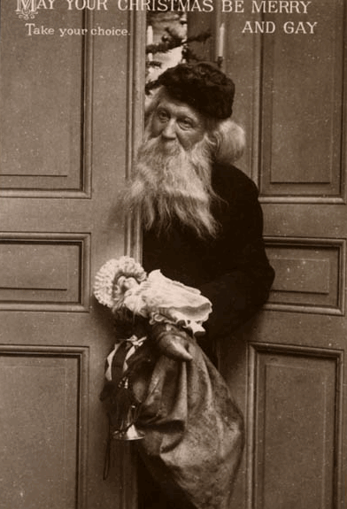 A vintage postcard with a greyscale photo of a Santa Claus coming through a door, with a Christmas message printed at the top.