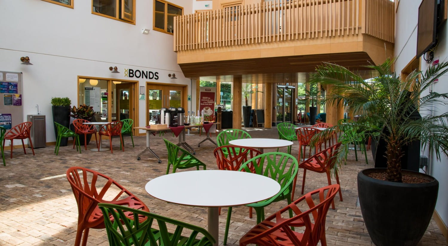 The foyer at Essex Business School, with red and green chairs around tables and Bonds cafe in the background.