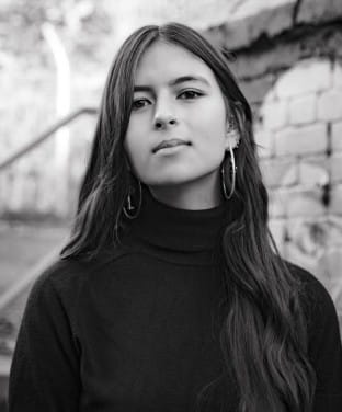 Black and white photo of Mya-Rose Craig, with a brick wall in the background.