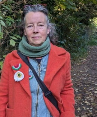 Susan Buckingham, standing outside with trees in the background.