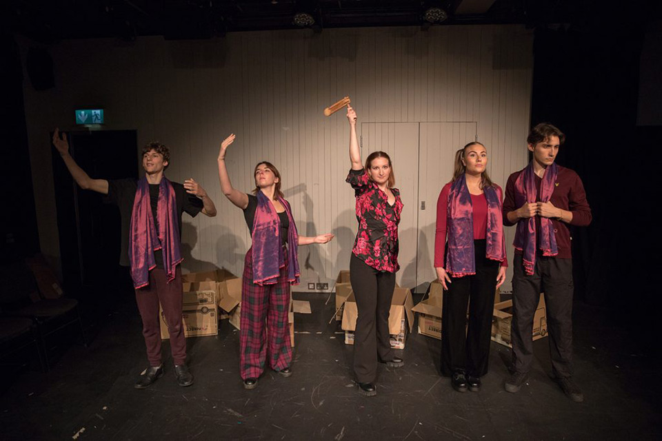 On stage performance shot of 'The S is Silent', five performers are stood on stage and in the centre is Marina Cusi Sanchez.