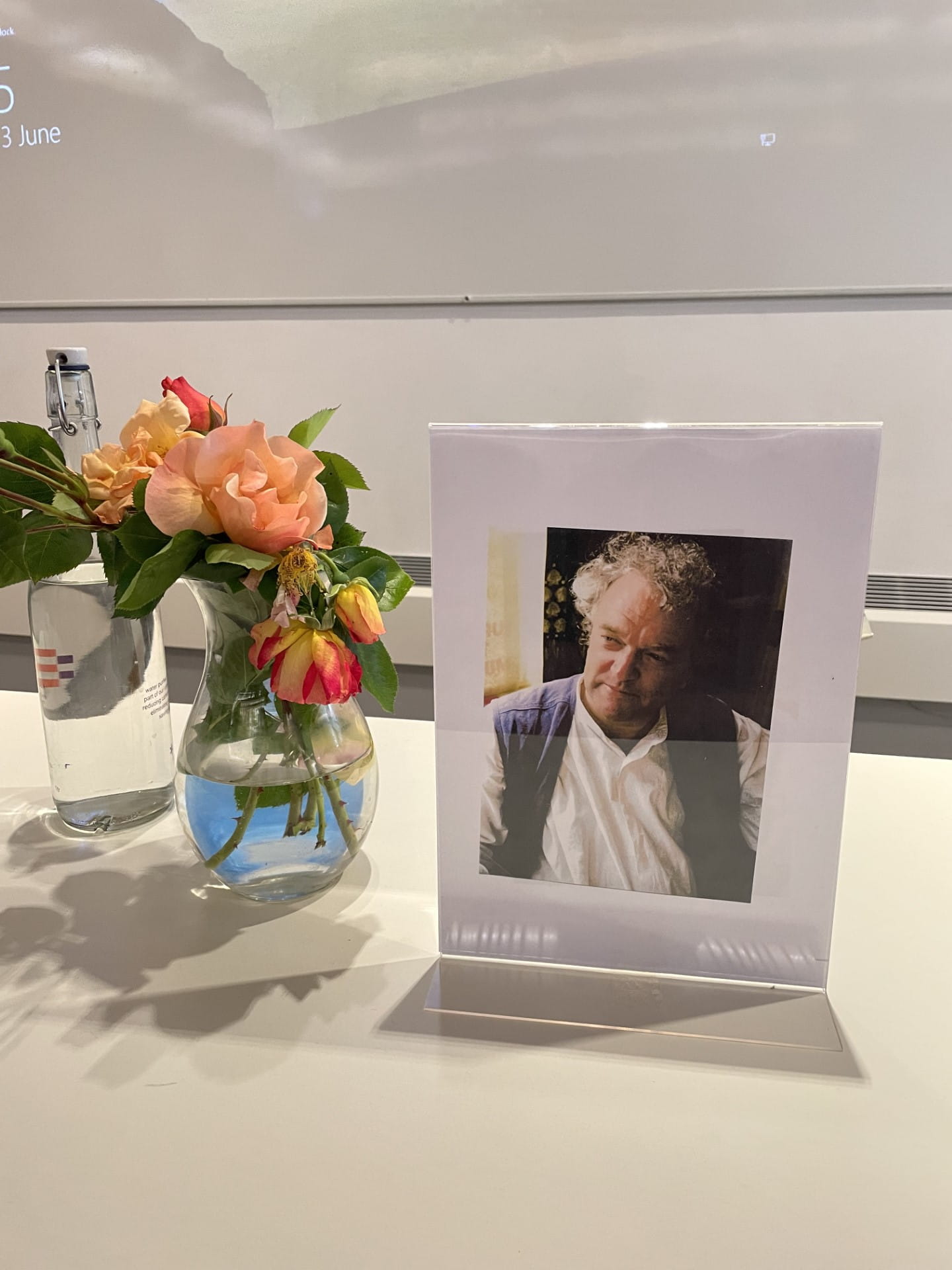 photo of a memorial table to Ken Plummer with a picture of him and a bowl of roses